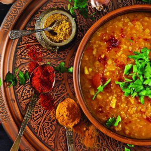 Indian dal. Food. Traditional Indian soup lentils.  Indian Dhal spicy curry in bowl, spices, herbs, rustic black wooden background. Top view. Authentic Indian dish. Banner. Flat lay from Sadiks concord tandoori